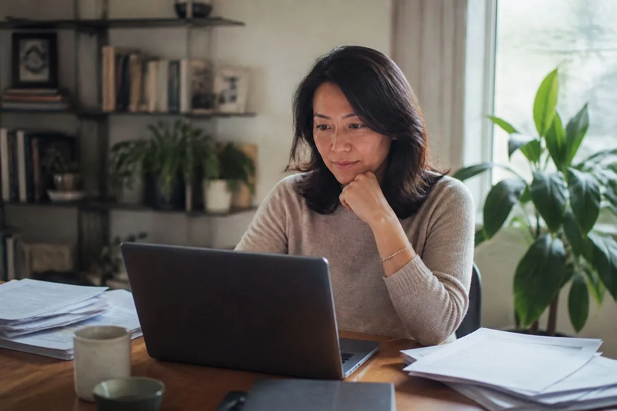A tech recruiter reviewing resumes on a laptop at a home office.