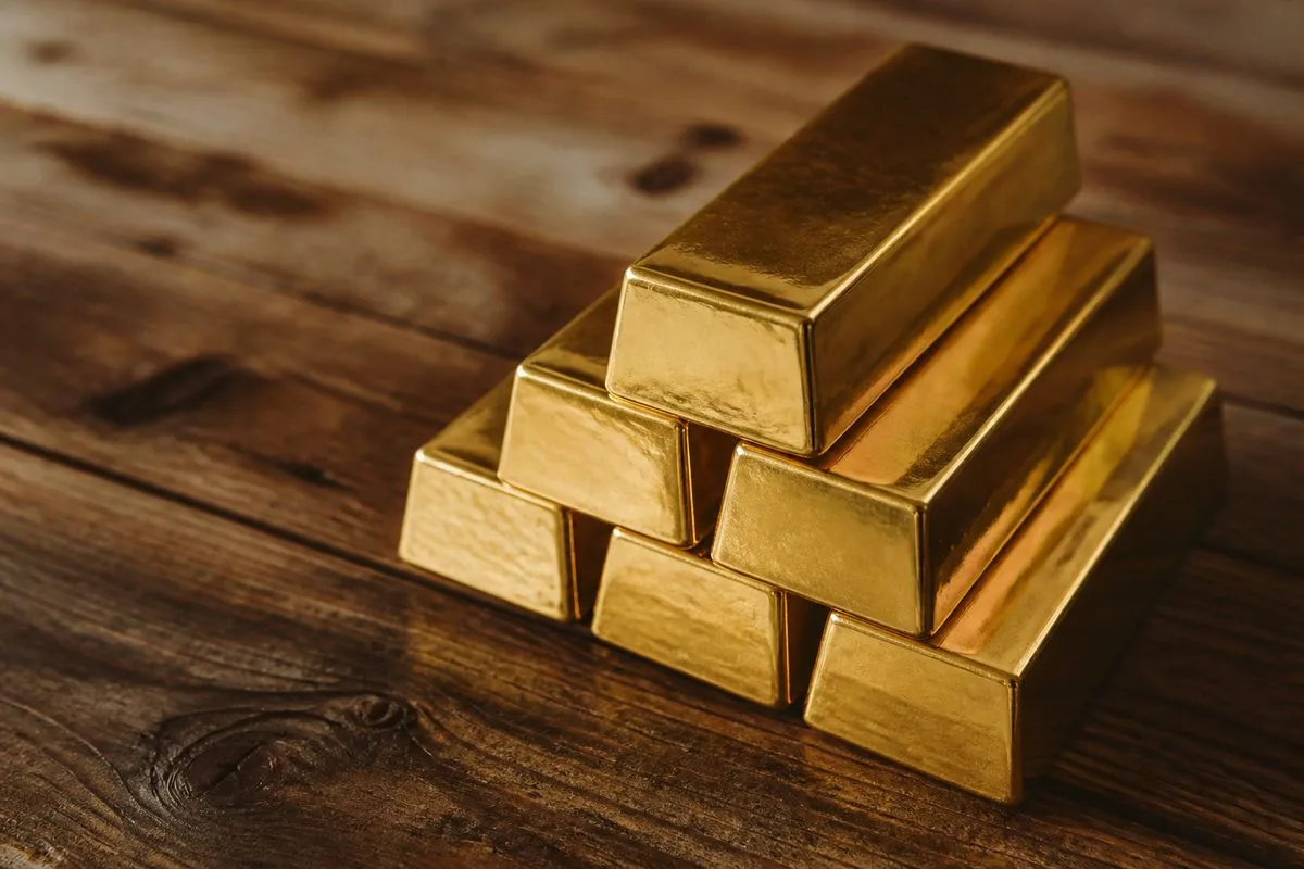 A close-up of gold bars stacked on a wooden table.