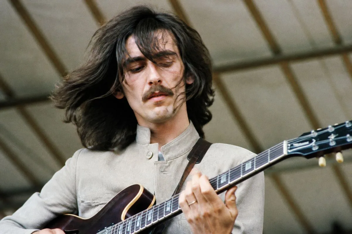 George Harrison playing guitar during a live concert