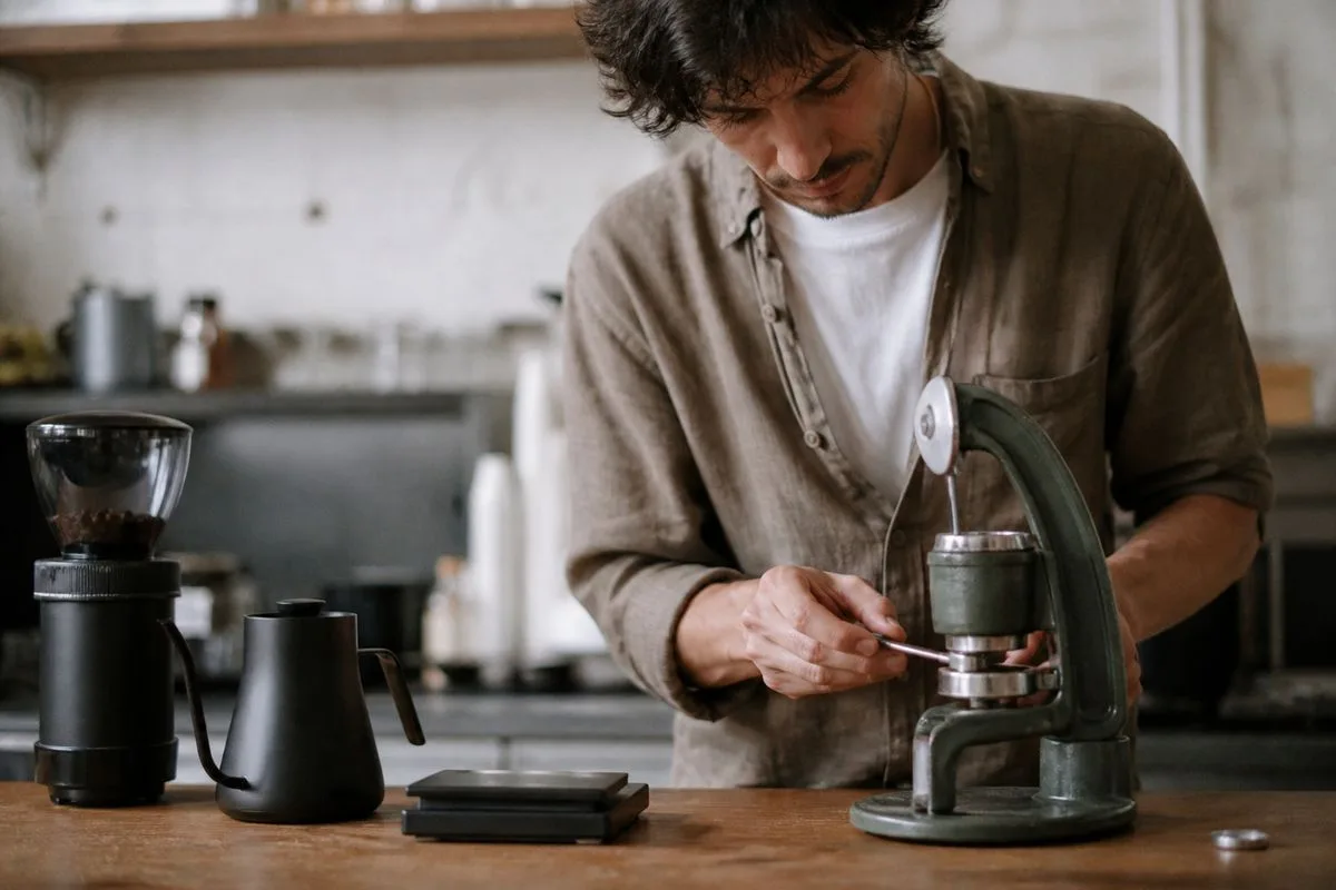 A person tamping coffee grounds into a manual espresso machine.