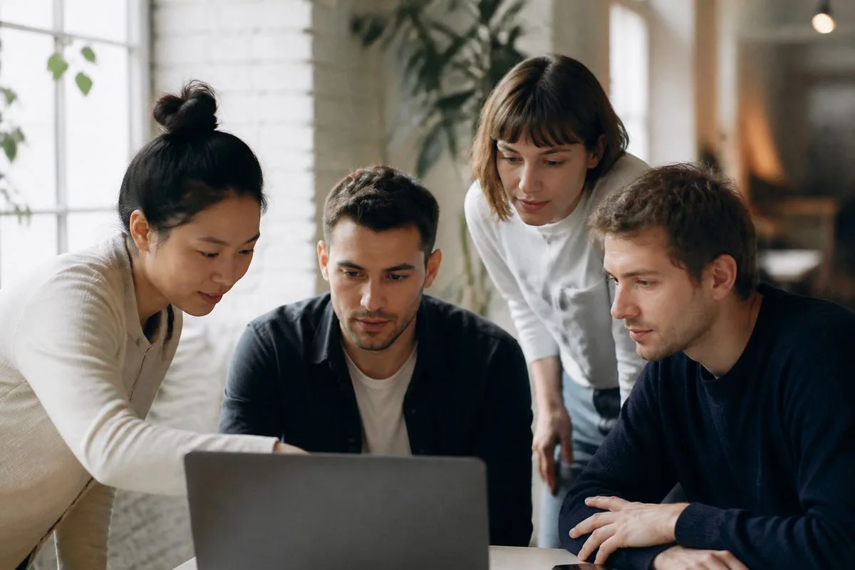 A team of designers and developers collaborating around a laptop.