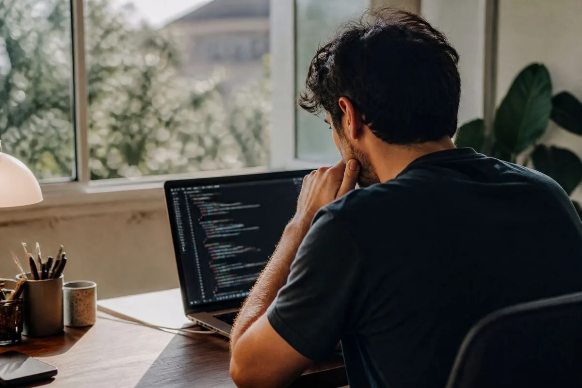 A software developer reviewing code on a laptop screen