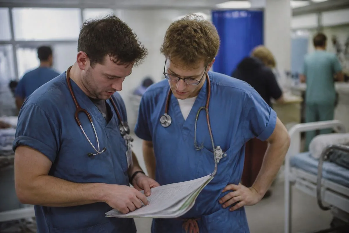 Junior doctors consulting over a patient's chart in A&E