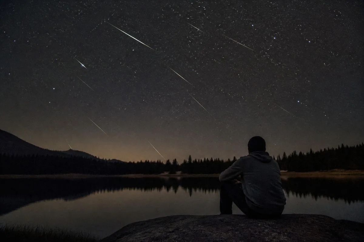 A person watching meteors streak across an October night sky