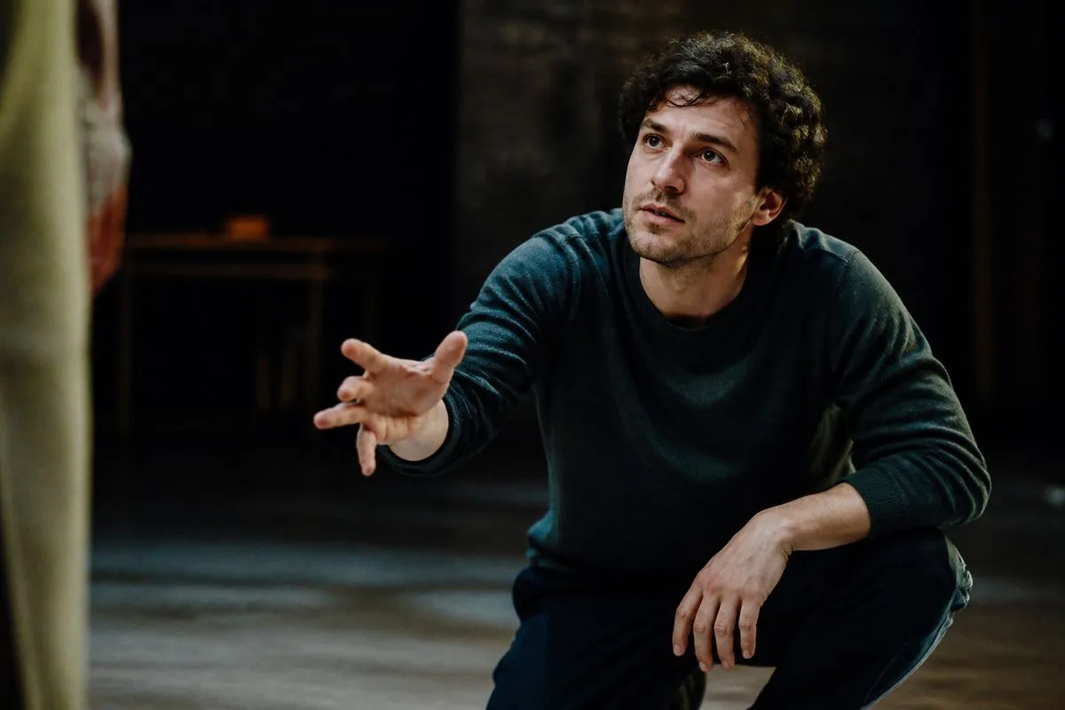 An actor rehearsing a dramatic scene on a dimly lit stage