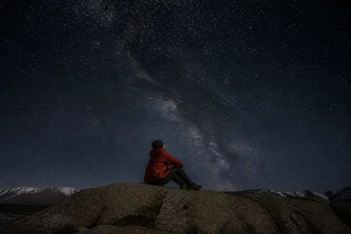 A person stargazing under a clear, dark night sky