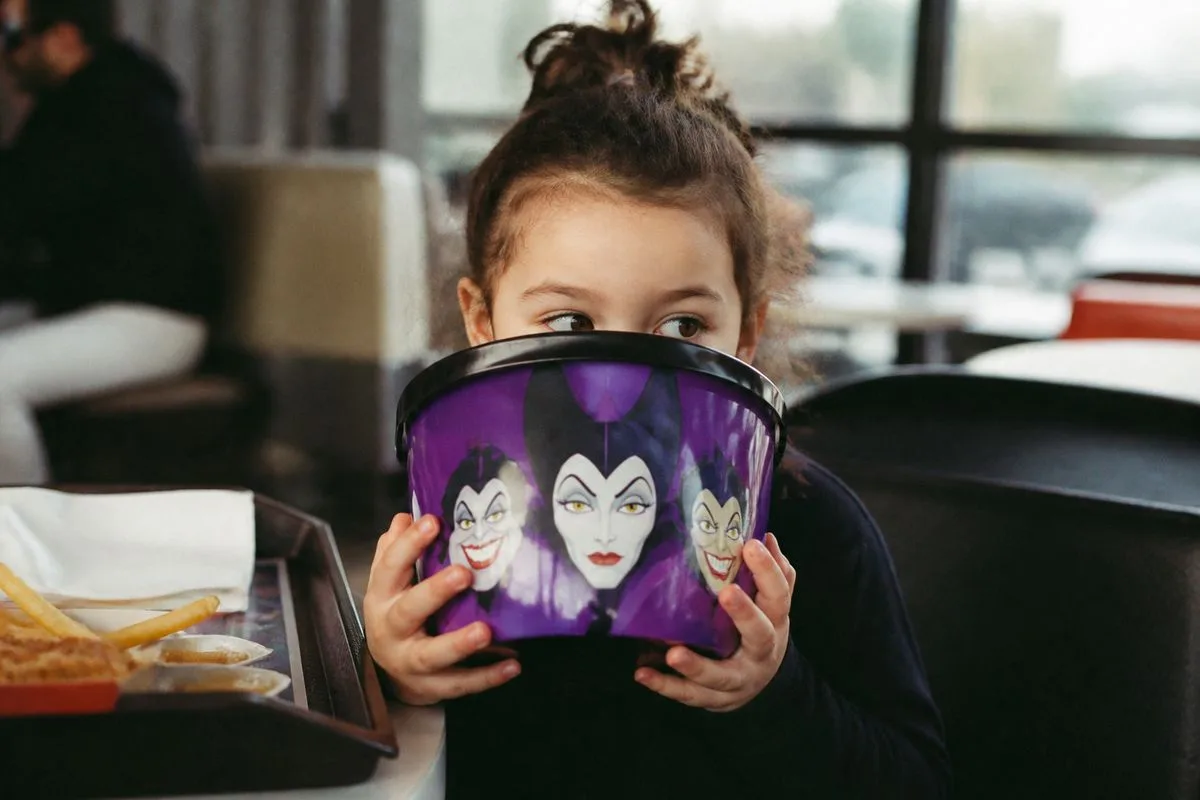 A child holding a Disney Villains Boo Bucket at McDonald's.