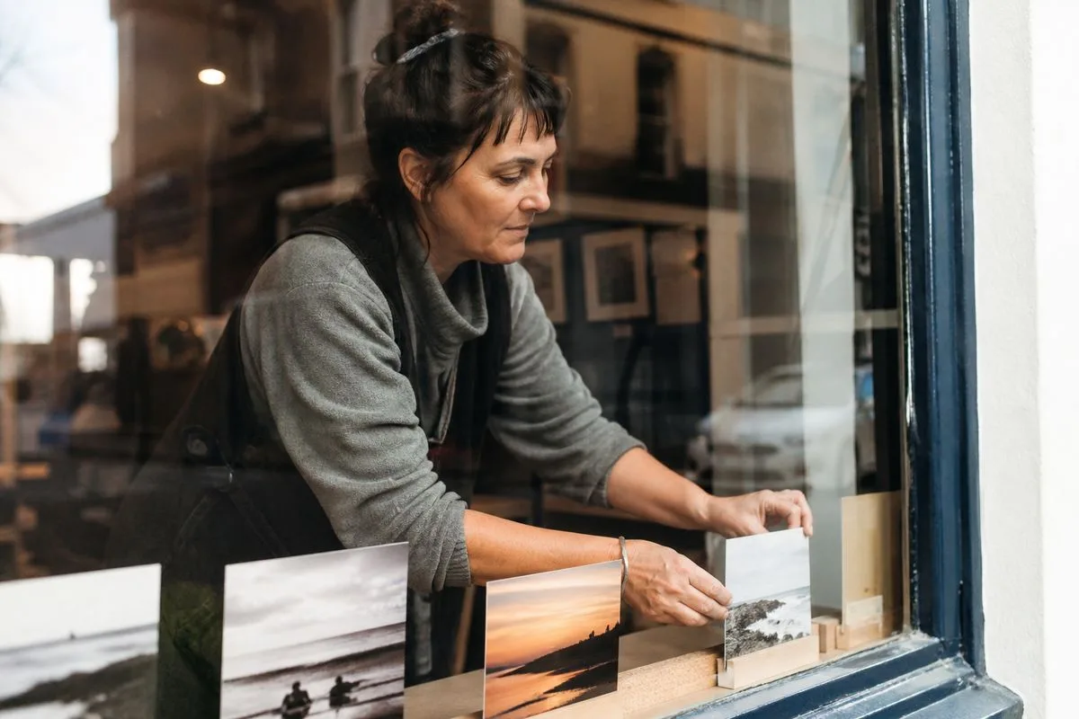 A local shop owner arranging advertisements in a window display