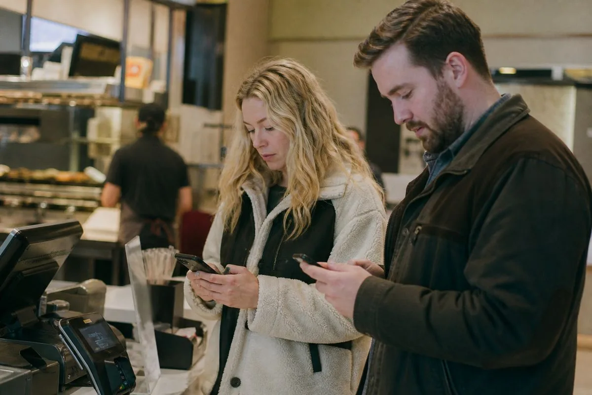 Customers using Arby's mobile app at a restaurant counter