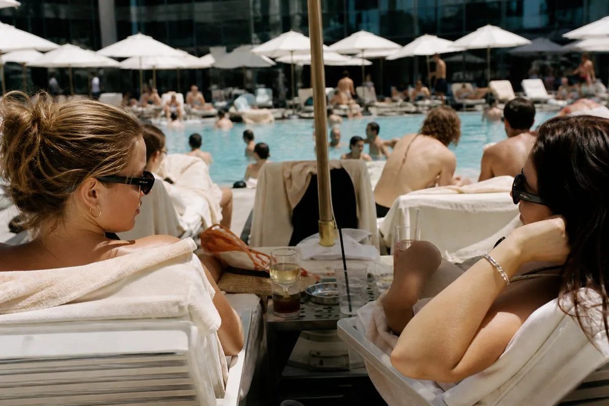 Guests relaxing by a crowded resort pool under umbrellas