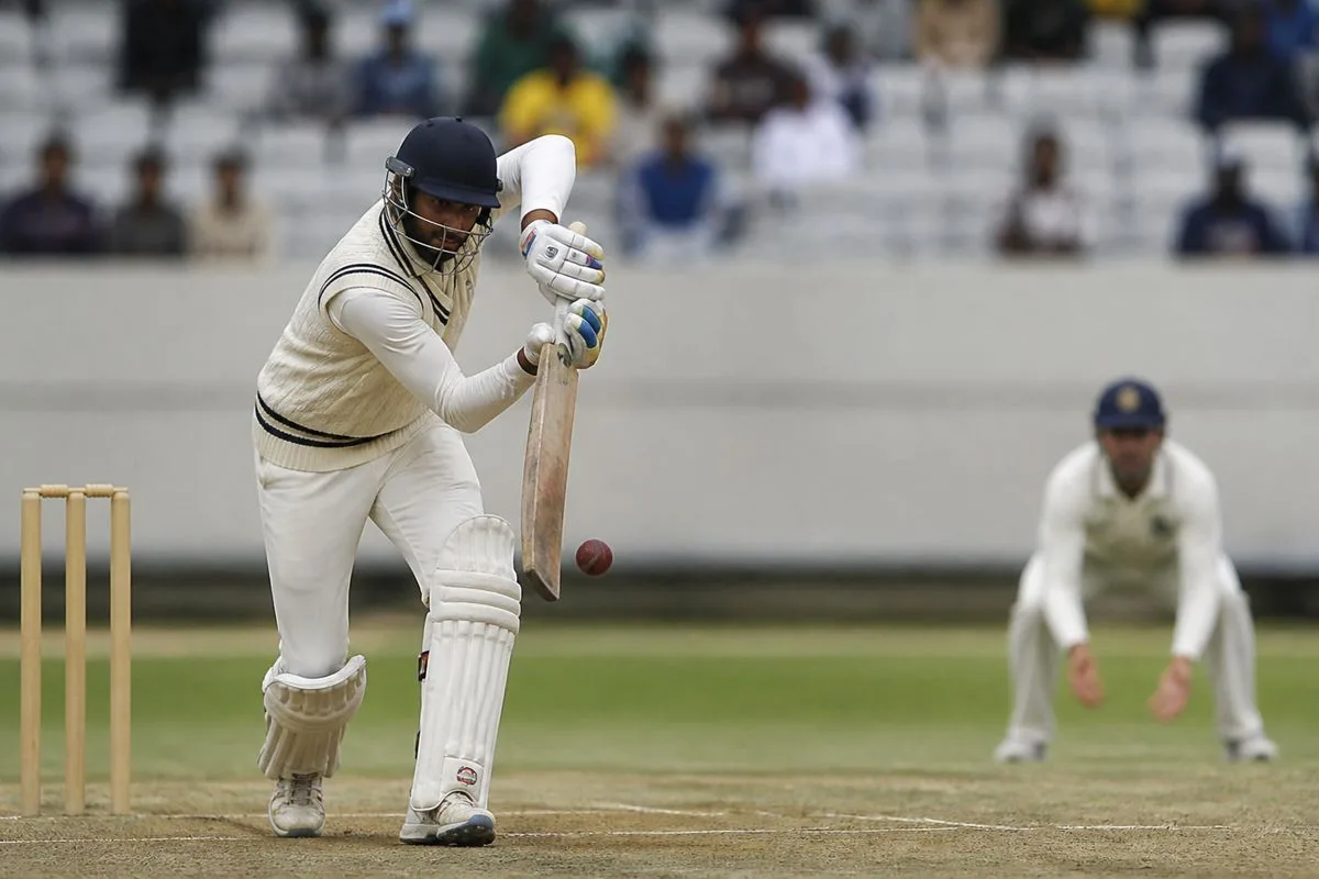 A batsman carefully playing a spin delivery in cricket match.