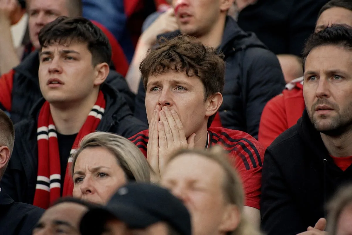 Manchester United fans anxiously watching a match in the stadium stands