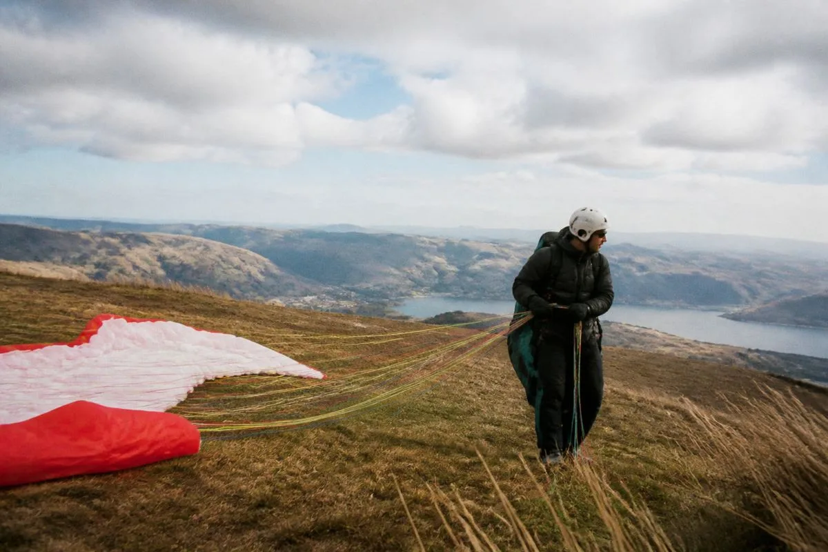 A paraglider preparing for takeoff on a windy hilltop