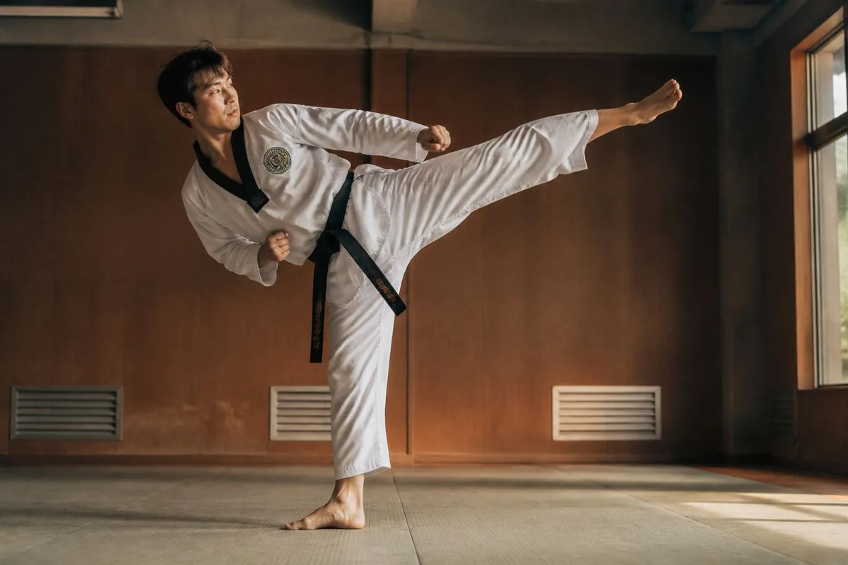 A martial artist practicing a taekwondo kick in a dojo