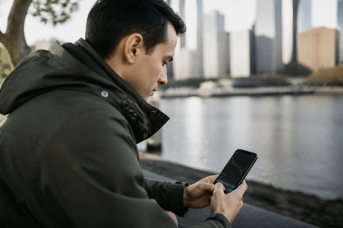 A person checking bitcoin prices on a smartphone outdoors