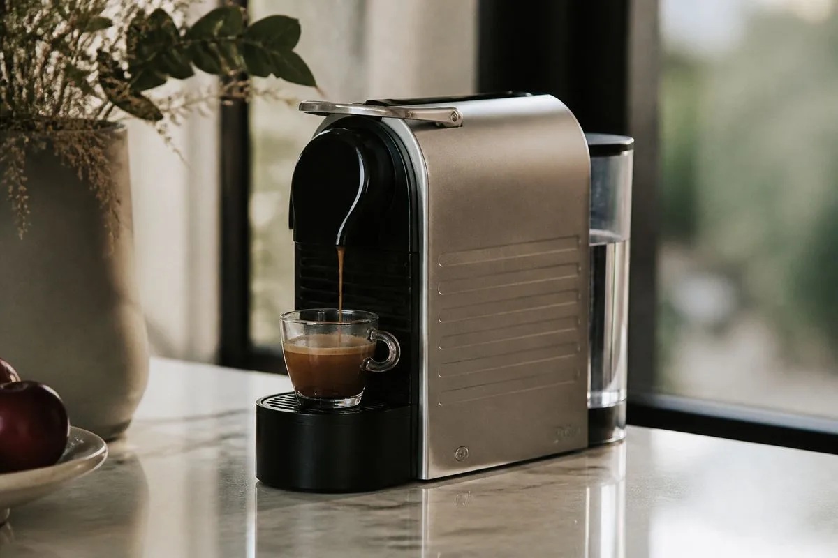 A sleek De’Longhi Nespresso machine brewing coffee.