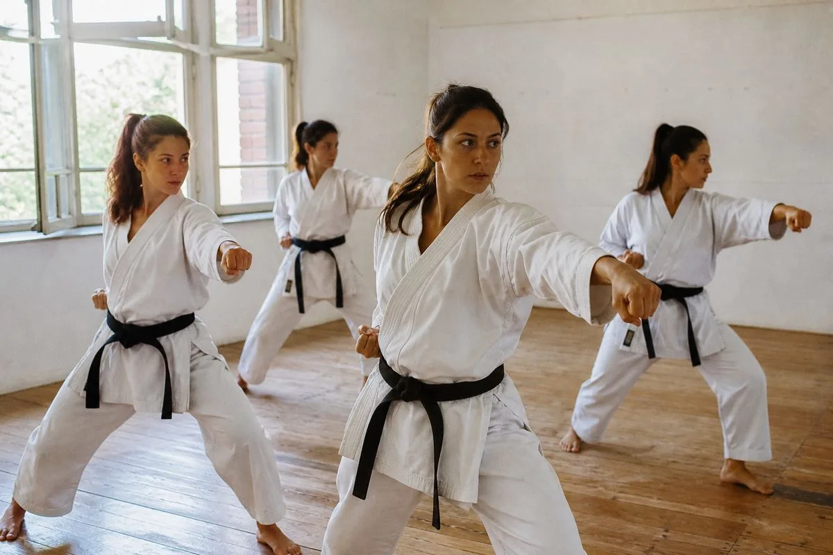 Women practicing karate moves in a bright dojo class