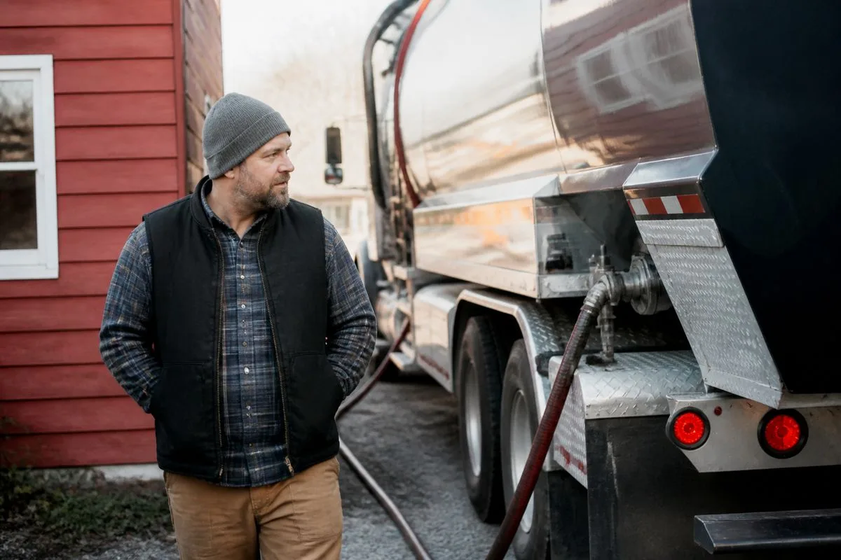A small business owner checking heating oil delivery outside shop