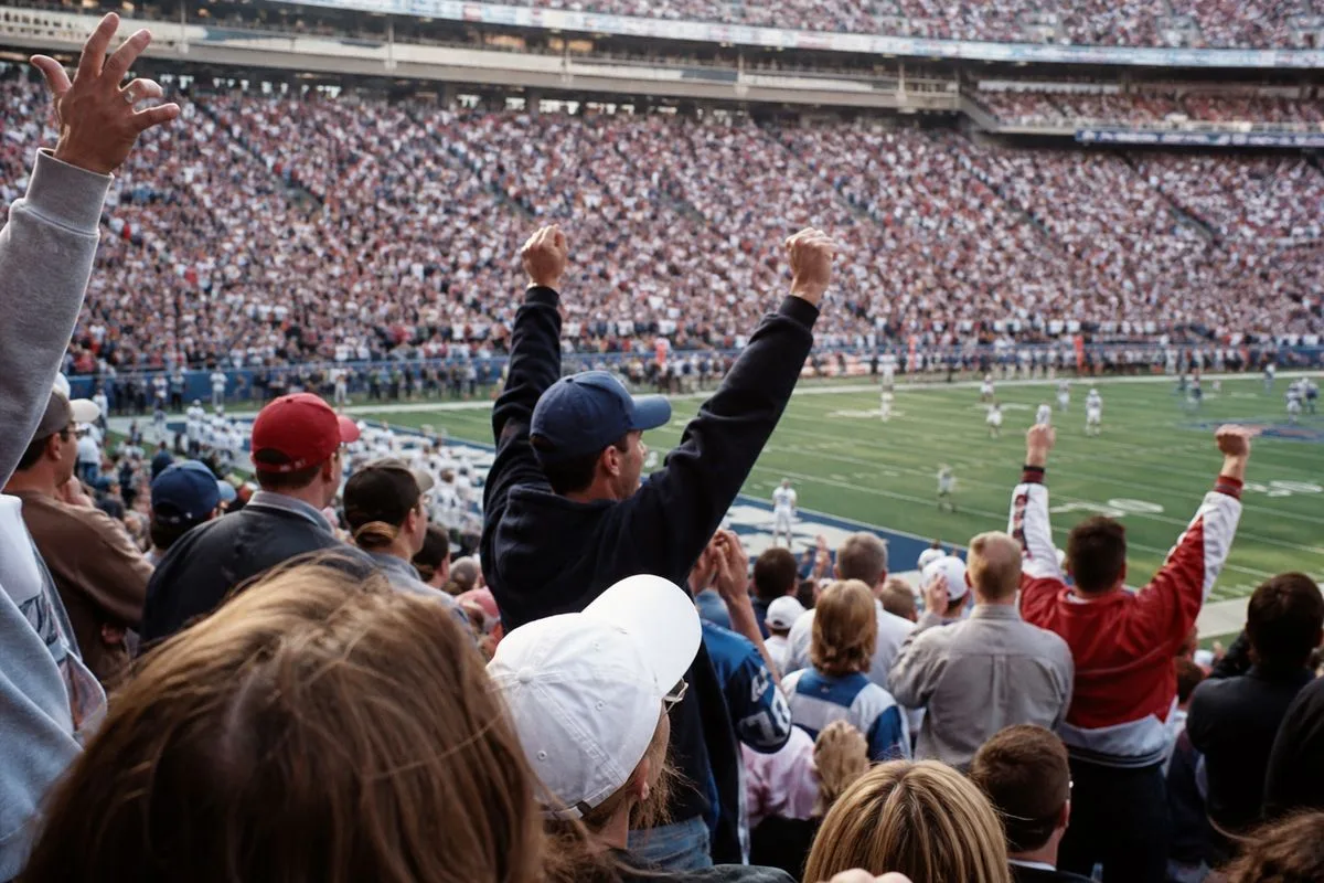 Fans cheering at a packed NFL stadium during kickoff