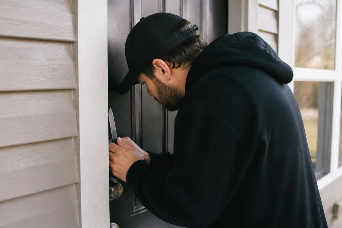 A man placing a knife beside his front door lock