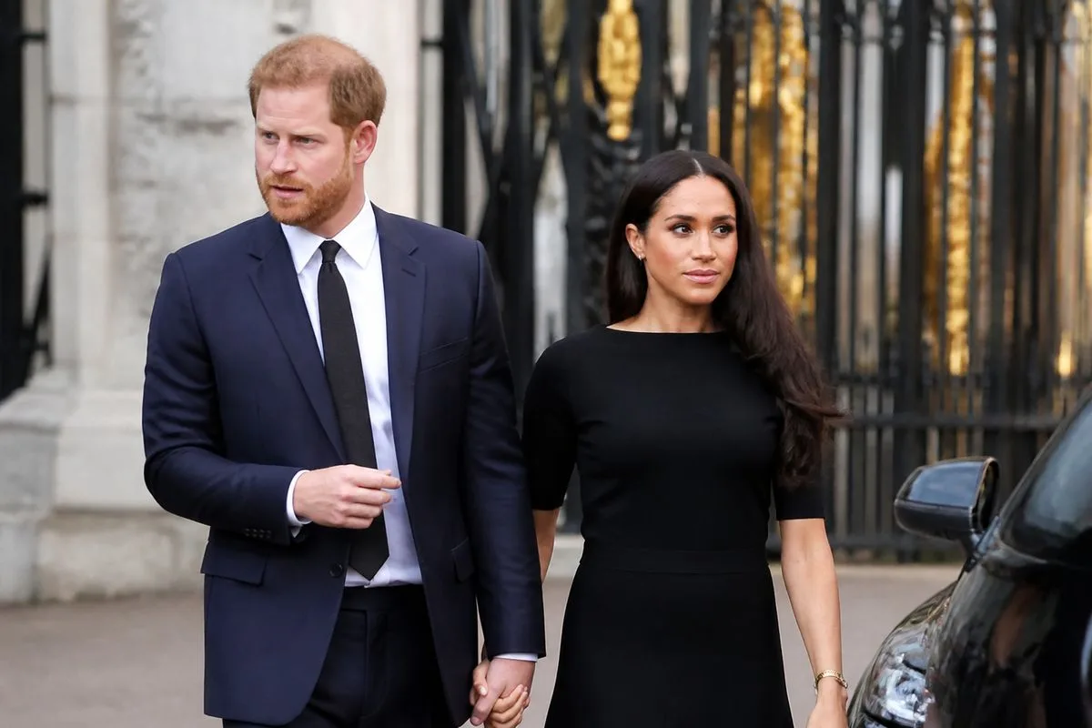 Prince Harry and Meghan walking outside a royal palace gate