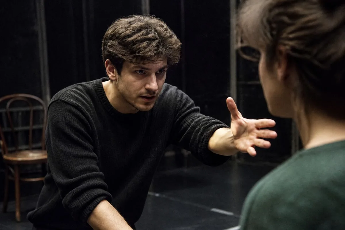Actor rehearsing a tense scene on a dimly lit stage