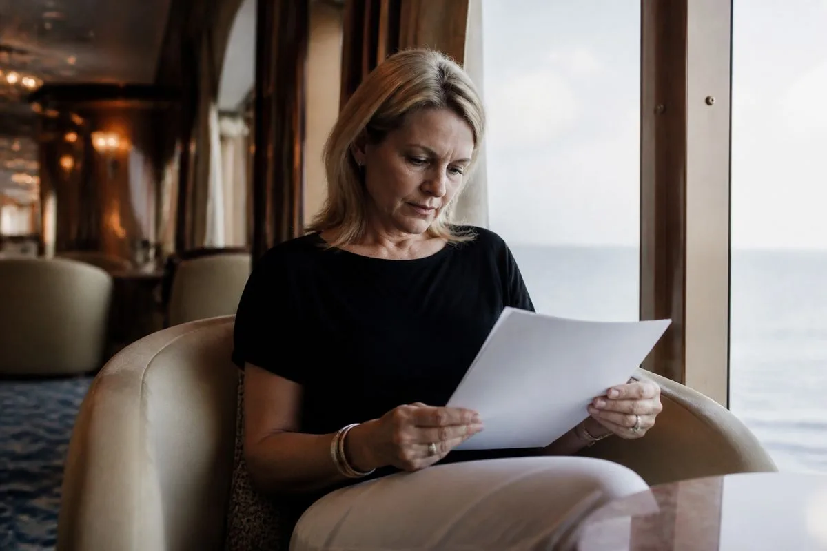 A passenger carefully reading a cruise settlement letter onboard a ship.