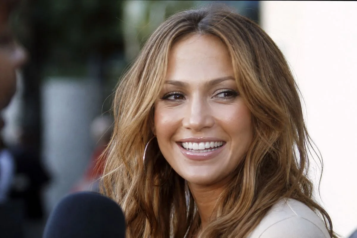 Jennifer Lopez smiling during a candid outdoor interview