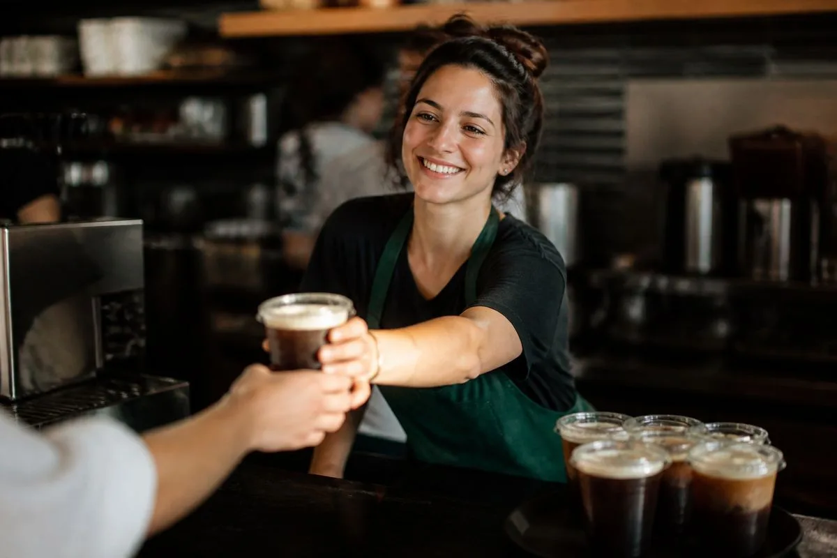 A barista serving iced espresso drinks at Starbucks counter