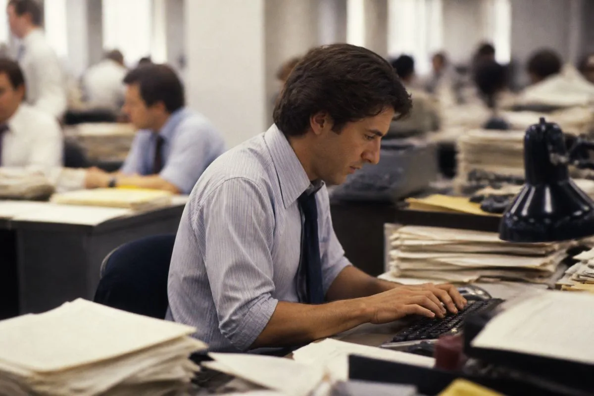 A journalist typing rapidly in a newsroom office