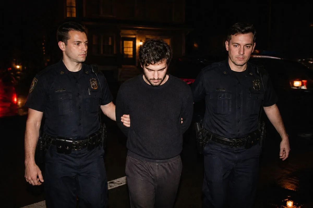 Police officers escorting a suspect in handcuffs at night