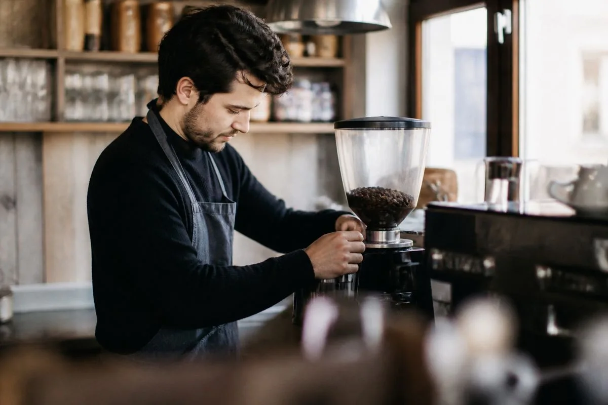 A barista grinding fresh coffee beans in a local café
