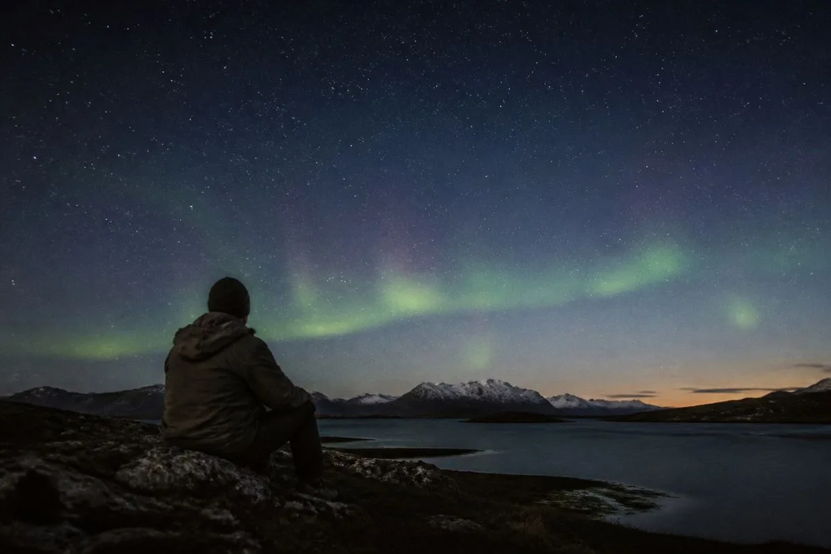 A person watching a faint aurora under a calm night sky