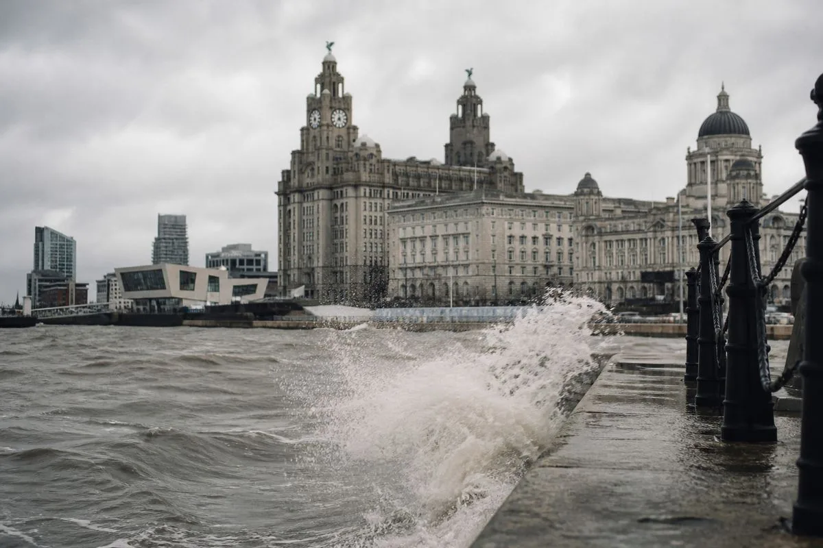 Cloudy Liverpool waterfront with waves crashing onshore