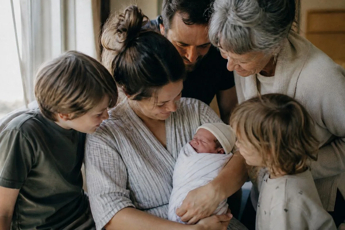 A mother holding her newborn while surrounded by family members
