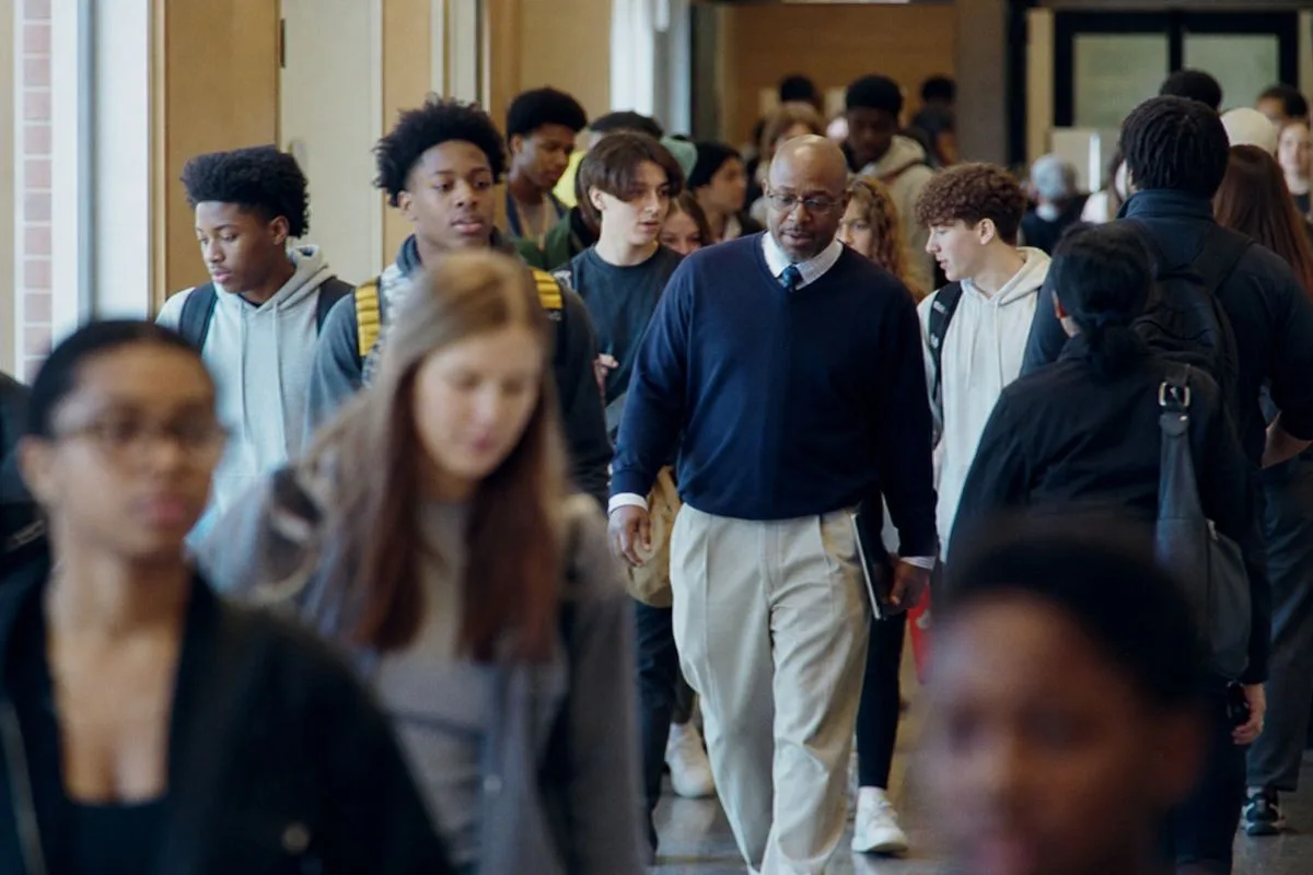 Students and staff quickly moving through a crowded school hallway at lunchtime
