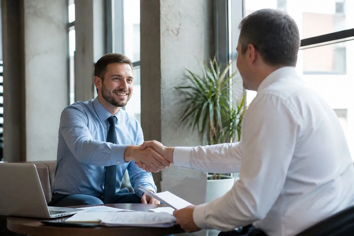 Two accountants shaking hands in a modern office.