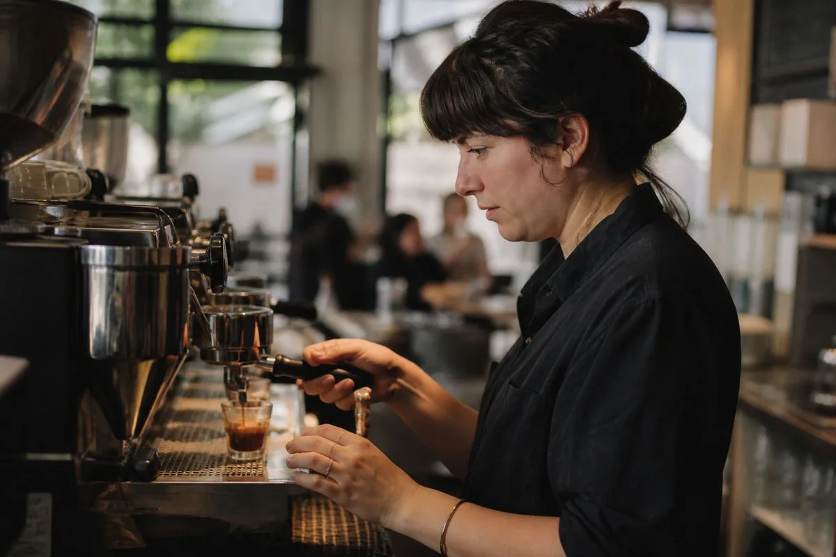 A barista carefully pulling an espresso shot in a busy café