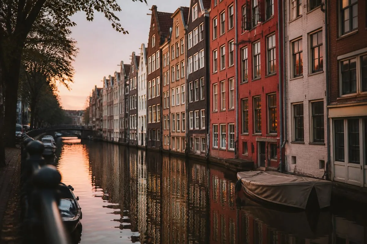 Narrow canal lined with colorful Amsterdam houses at dusk