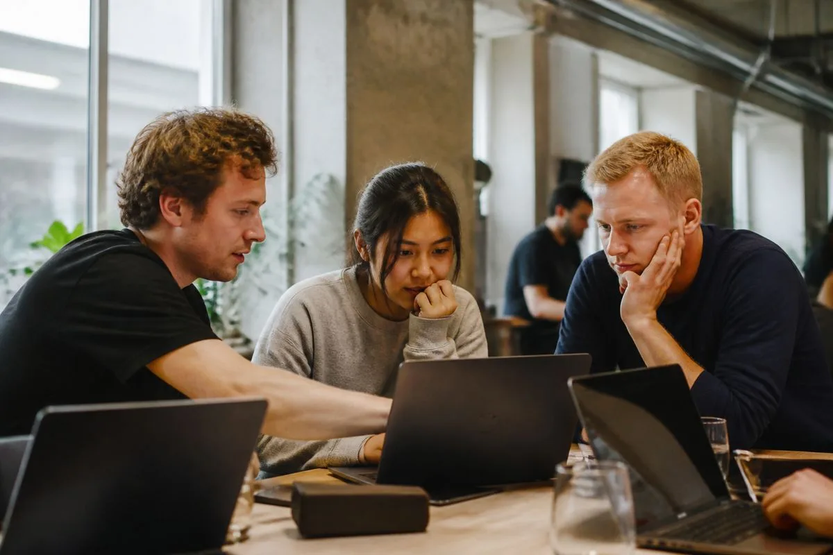 Developers collaborating around laptops in a modern office.