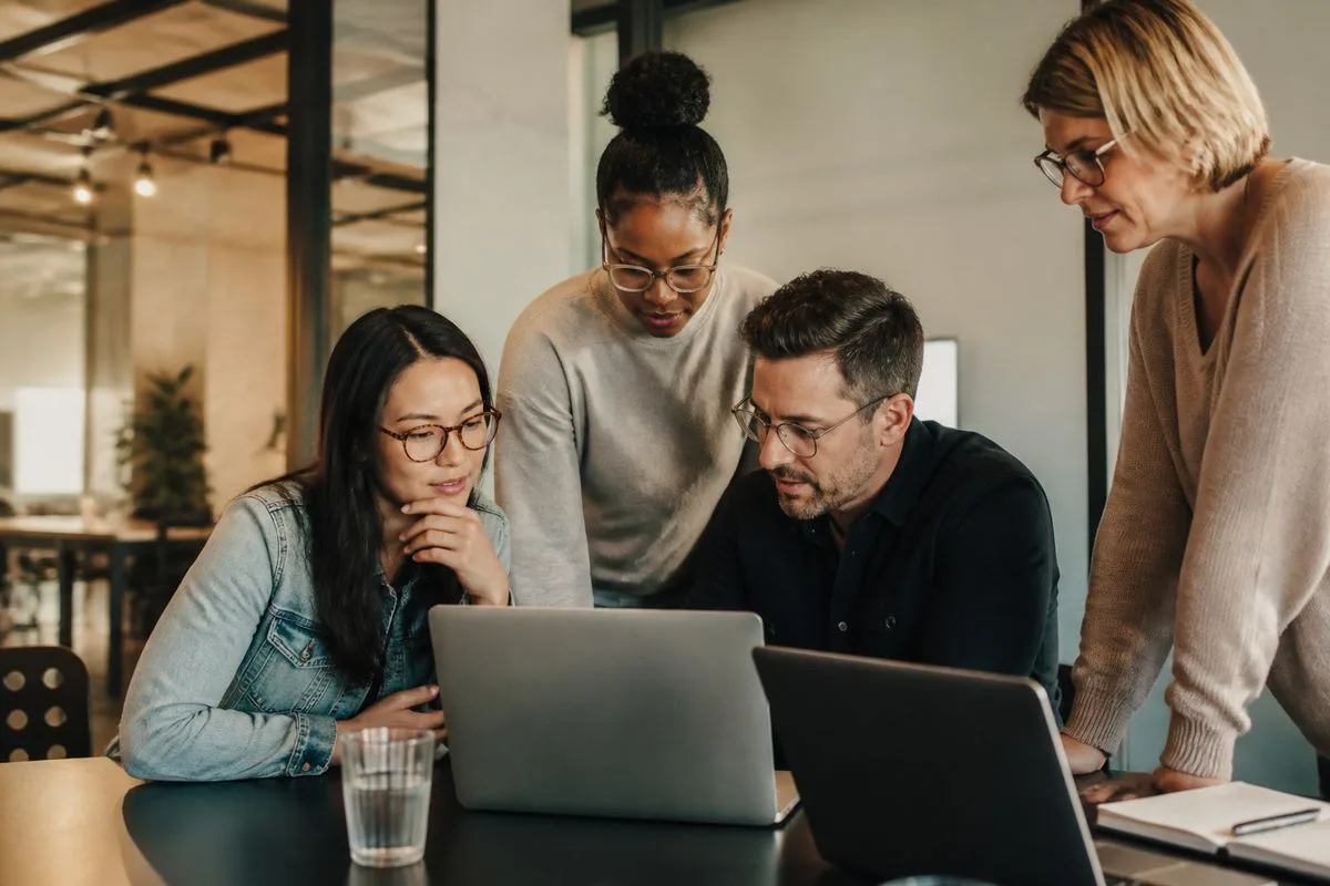 Team of professionals collaborating over laptops in a modern office.