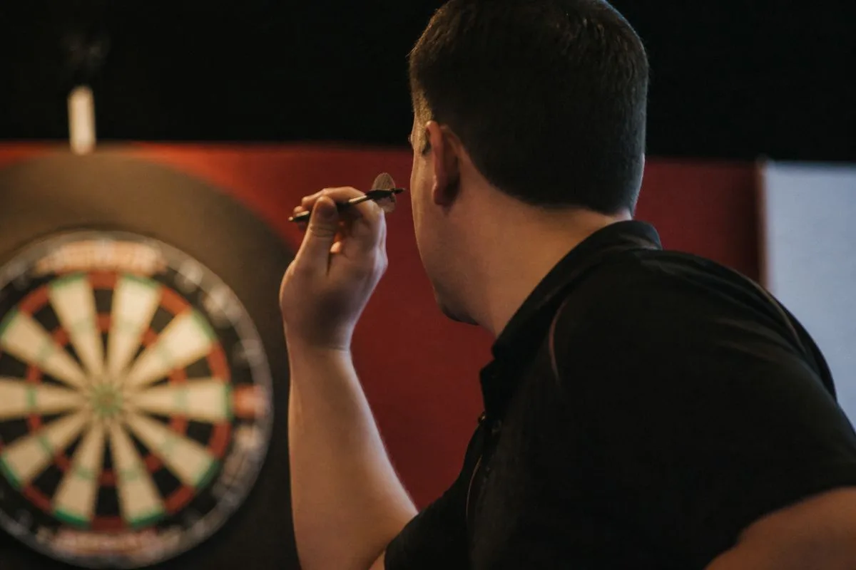 A darts player aiming at the board during a match.