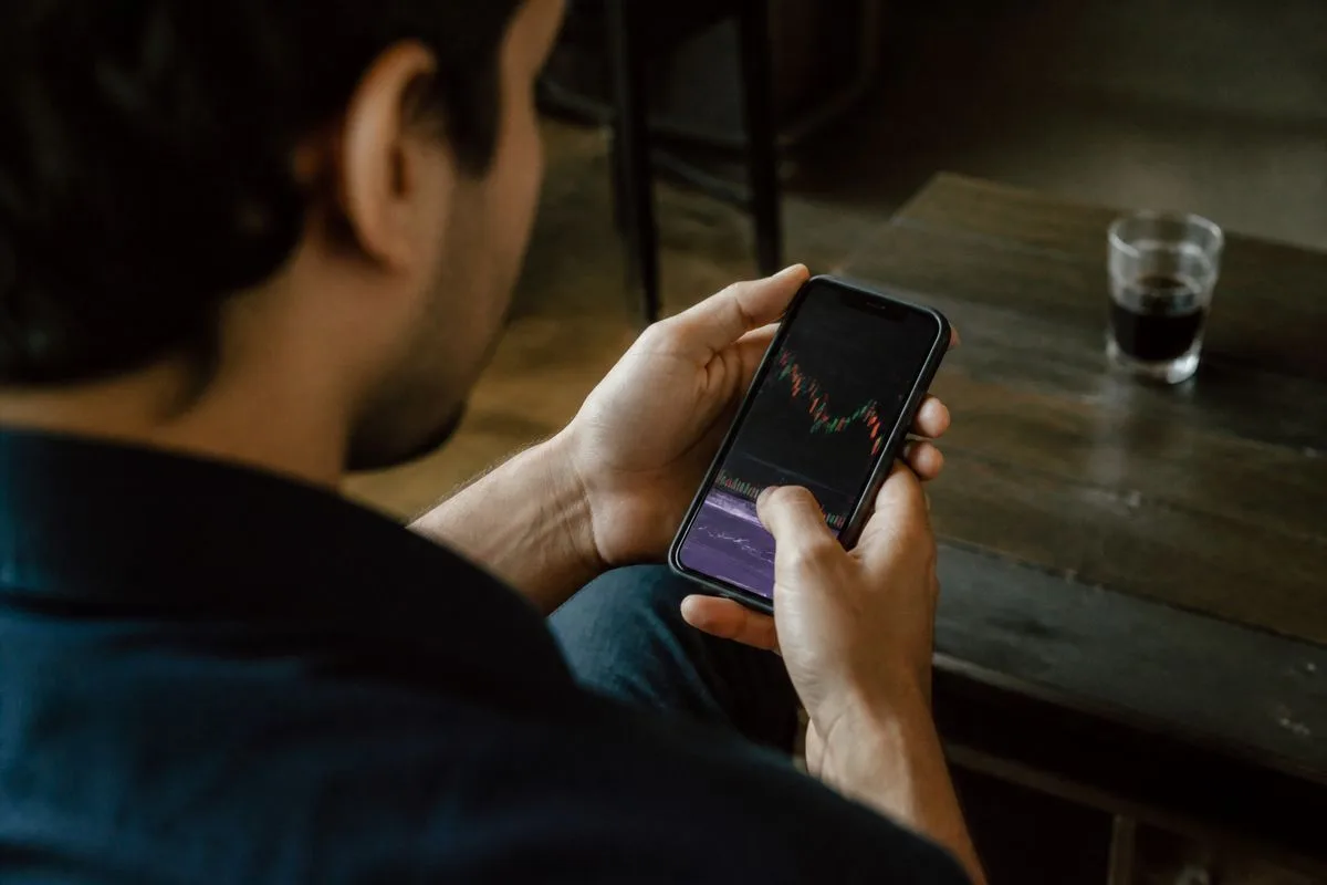 A person scrolling through stock market apps on a smartphone