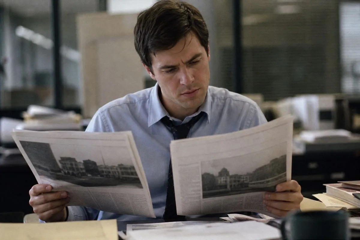 A journalist comparing two newspapers with different headlines.